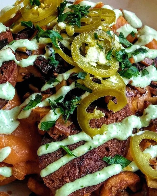 up close &amp; personal with our DY-NA-MITE 🍟🧨 these waffle fries are topped with pickled jalape&ntilde;os, seitan fak'n bacon bits, creamy jalape&ntilde;o-cilantro aioli, house-made merguez sausage, and dreamy cheese sauce 🧀🌶 rad photo by our go